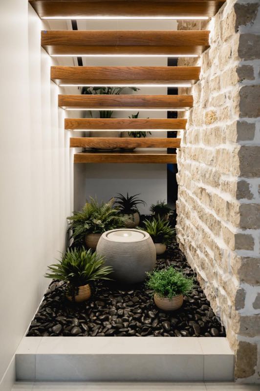 Floating oak stair over a planted stone wall