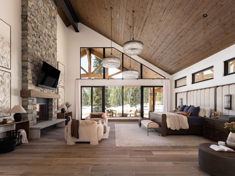 Great room seating around the stone fireplace, looking out to the trees