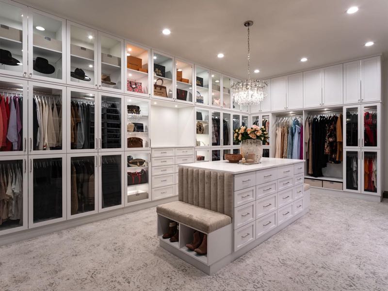 Primary closet with glass-front wardrobes and a centre island