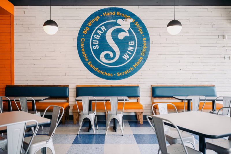 Sugarwings dining room with the logo on the white brick wall