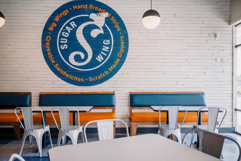 Booths under the Sugarwings logo on the white brick wall