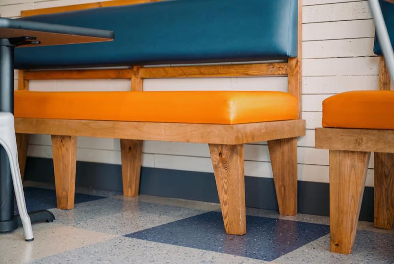 Booth detail: navy and orange upholstery on oak